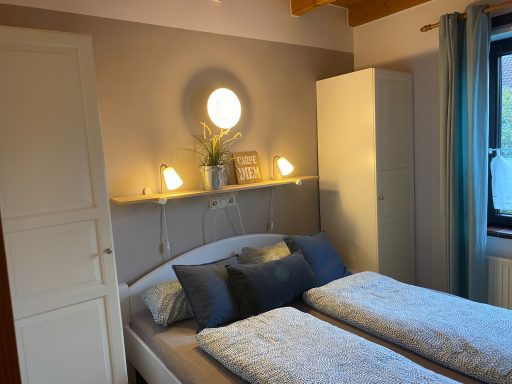 Helles Schlafzimmer mit zwei Einzelbetten, einem Nachttisch und einem weißen Kleiderschrank.