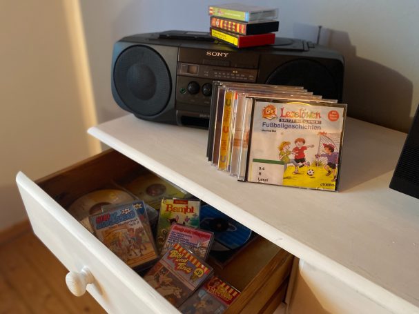 CD-Player mit CDs und einer Schublade voller Kassetten und Spielen.