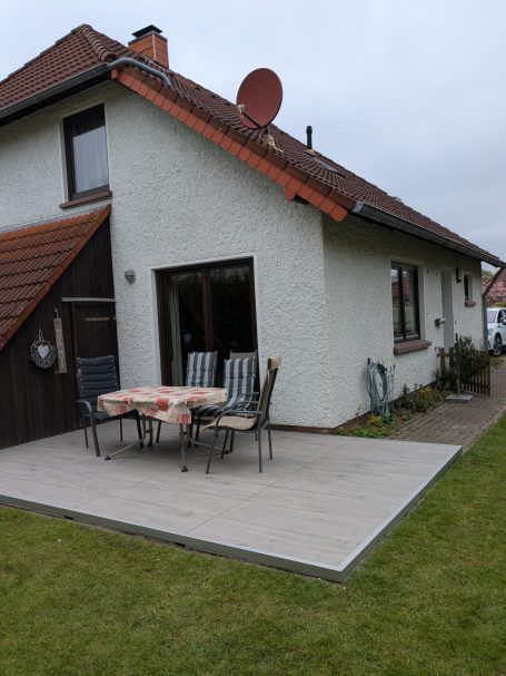 Ein Haus mit Terrasse und Gartenmöbeln, Satellitenschüssel auf dem Dach.